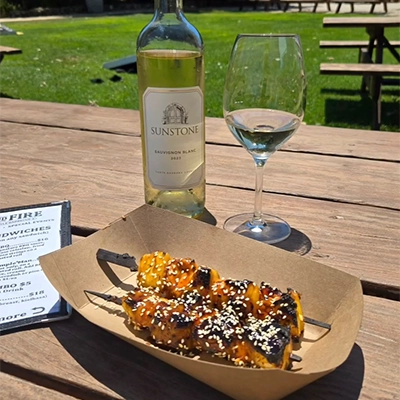 a bottle of wine and a grilled skewer